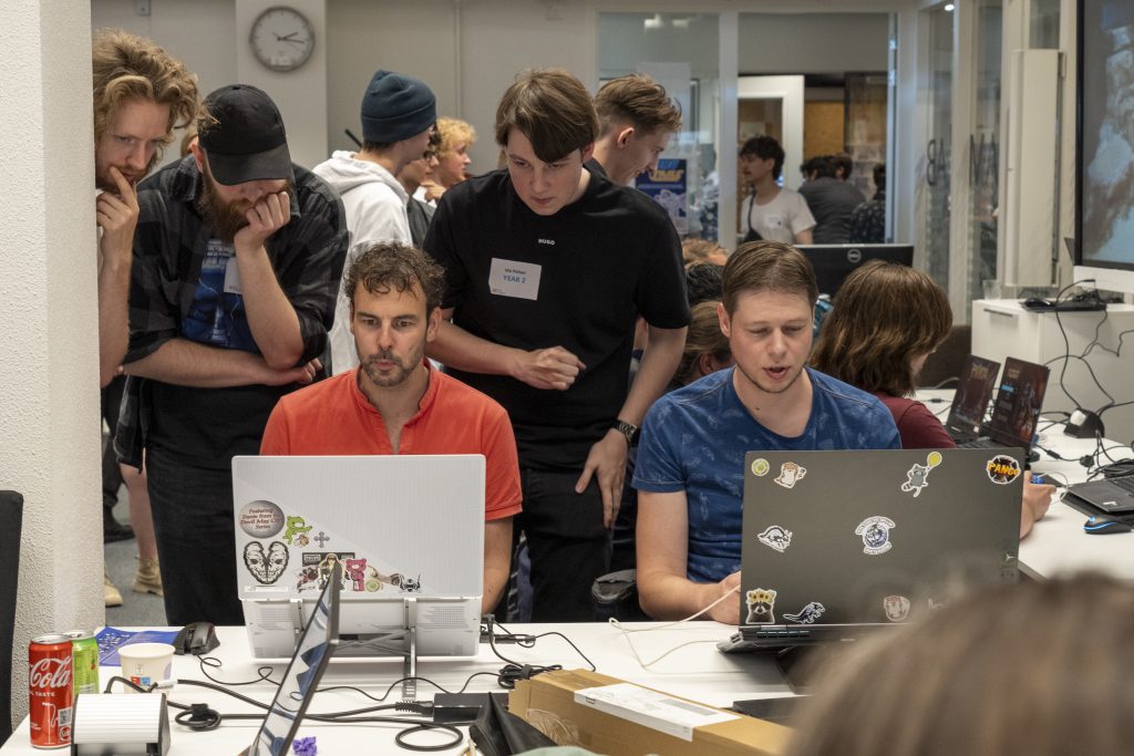 Students watching an industry expert working on a laptop.